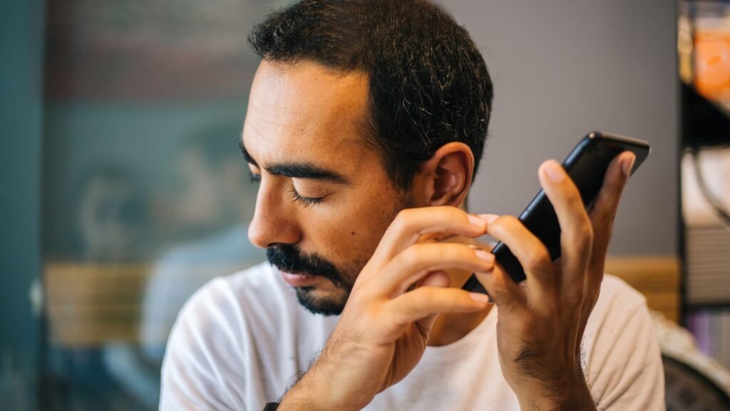 Homem com deficiência visual escuta audiodescrição no celular.